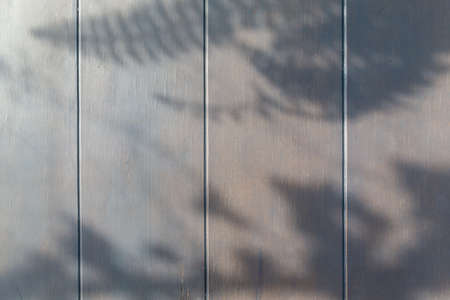 Wooden table background in a evening light. With shadows from a leaves.