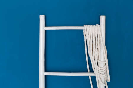 ladder with rope lean on blue wall background.の写真素材