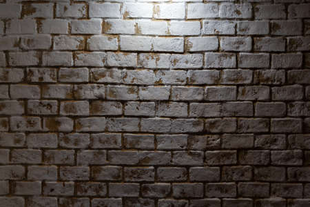 Aged birck wall backdrop with light from center top.の写真素材