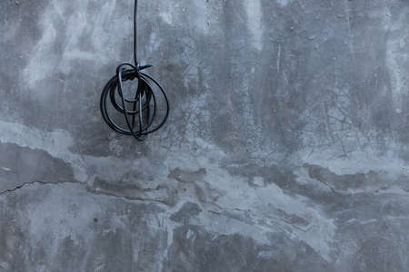 roll up of black electric wires with cement wall background.の写真素材