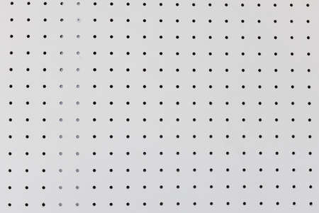 orderly holes or dot rows and columns on white pegboard wall.の写真素材
