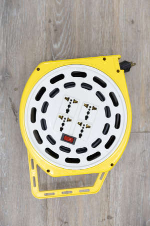 top view of white and yellow roll plastic portable multiple socket outlet plug with switch on wooded...