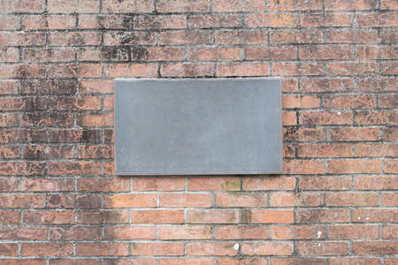 Blank iron house number plate on old brick wall with weathered and stained texture background.の写真素材