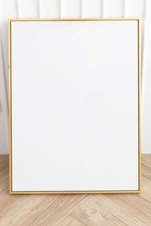 blank golden frame with white wall on wooden floor.