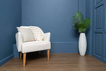 front view of single comfortable wooden leather chair with blue interior wall.