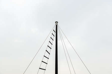 top of small ship masts in sky cloud background copy space with rope ladder used to observe from peak of the highest post.の写真素材