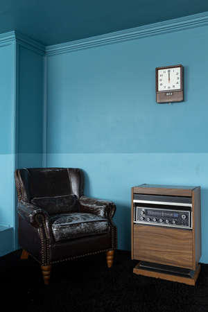 interior view of old styled black vintage leather armchair and antique wooden radio receiver box on...