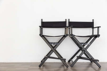 front view of black two director chair in film industry on wooden floor with white wall backgroundの写真素材
