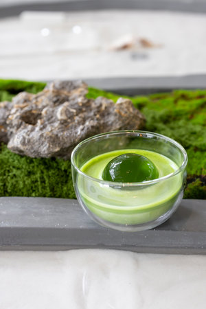 Matcha or green tea latte in transparent glass with round ice, also known as ice spheres