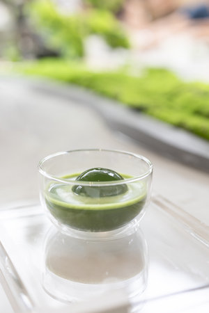 Japanese Matcha or green tea latte in transparent glass with round ice, also known as ice spheres