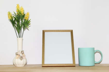 Photo frame mockup and vase with yellow flowers on wooden tableの写真素材