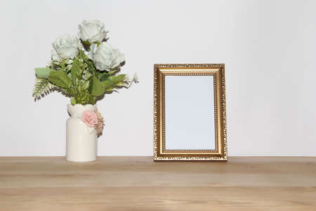 Photo frame mockup with roses in vase on wooden table.の写真素材