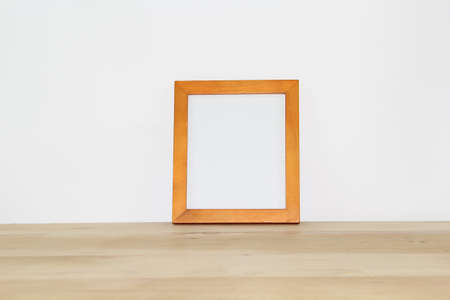 Wooden photo frame on a wooden table against a white wall.の写真素材