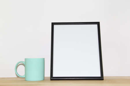 Mockup blank photo frame with cup of coffee or tea on wooden table.の写真素材