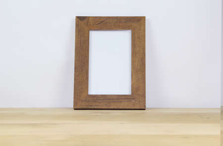 Wooden picture frame on wooden table and white wall background, stock photoの写真素材
