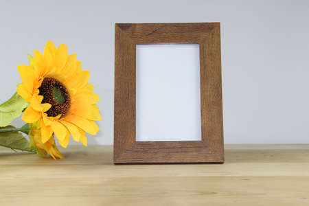 Photo frame with sunflower on wooden table and white wall background.の写真素材