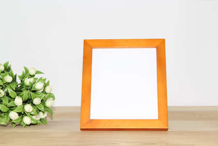 Photo frame mockup with white roses bouquet on wooden table.の写真素材
