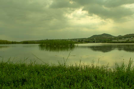 Landscape view of lake and mountain with green grass on the foregroundの写真素材