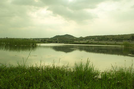 Landscape of a lake with green grass and mountains in the backgroundの写真素材