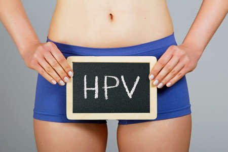 Women's health concept. Young woman holds a small chalkboard with HPV inscription