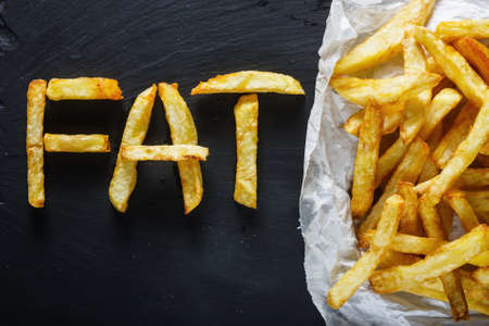 Unhealthy food concept - french fries on slate board