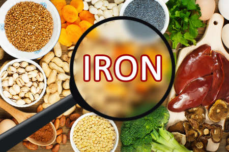 Collection iron rich foods as liver, buckwheat, eggs, parsley leaves, dried apricots, cocoa, lentil, bean, blue poppy seed, broccoli, dried mushrooms, peanuts and pistachios on wooden table.の写真素材