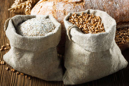 Wheat and wholemeal flour in small bags on wooden tableの写真素材