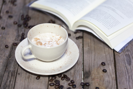 Cup of coffee and book on a wooden tableの写真素材