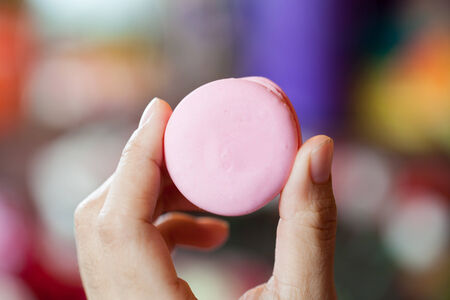 Pink macaroons in the hands of girl on bokeh backgroundの写真素材