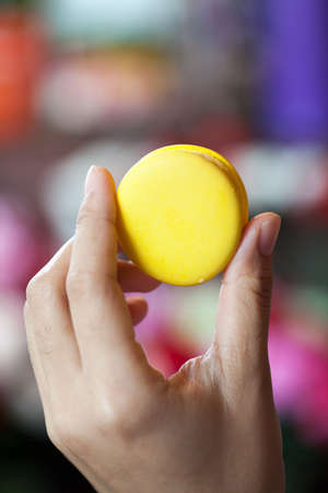 Yellow macaroons in the hands of girl on bokeh backgroundの写真素材
