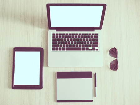 Laptop Tablet Pen Tablet and Sunglasses on wooden table Designer Desktopの写真素材