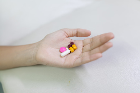 Closeup shot of a woman showing capsule pill. Female hand holding a medicine. Shallow depth of field with focus on capsule pill.の写真素材