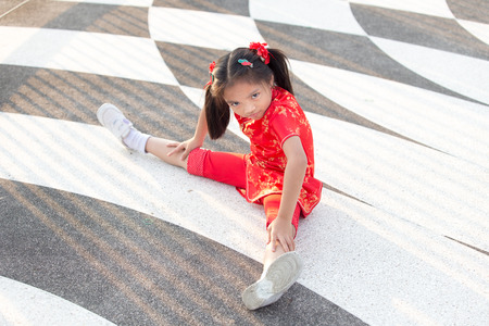 Beautiful Asian kids girl with Chinese traditional dress Cheongsam ( Seated Wide Legged Straddle )の写真素材