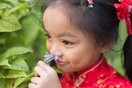 Portrait of a Six year old little girl outdoor in a garden smelling the flowers.の写真素材