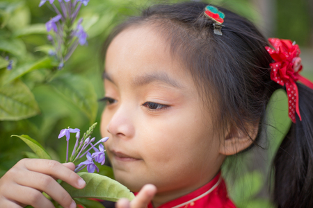 Portrait of a Six year old little girl outdoor in a garden smelling the flowers.の写真素材