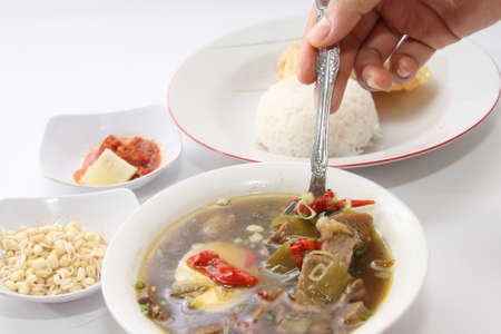 Rawon or Indonesian beef black soup, served with white rice, baby bean sprouts, chili sauce and emping chipsの写真素材