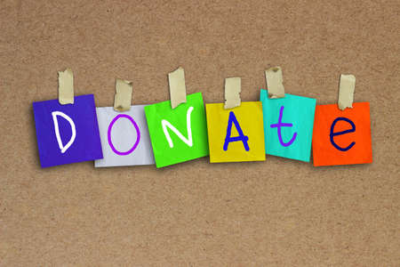 The word Donate written on sticky colored paper over corkboard texture backgroundの写真素材