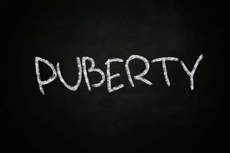 The word Puberty written with chalk on blackboardの写真素材