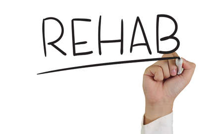 Image of a hand holding marker and write Rehab word isolated on whiteの写真素材