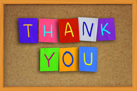 The word thank you written on sticky colored paper over cork boardの写真素材