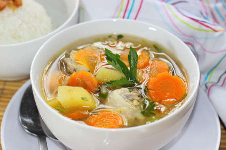 A bowl of Chicken Soup served with slices of potato and carrotsの写真素材