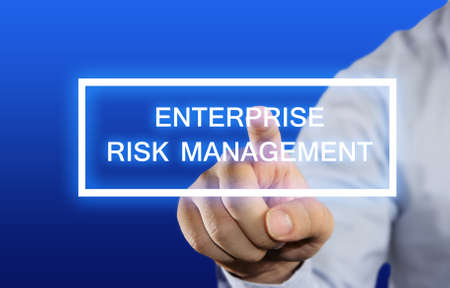 Business concept image of a businessman clicking Enterprise Risk Management button on virtual screen over blue backgroundの写真素材