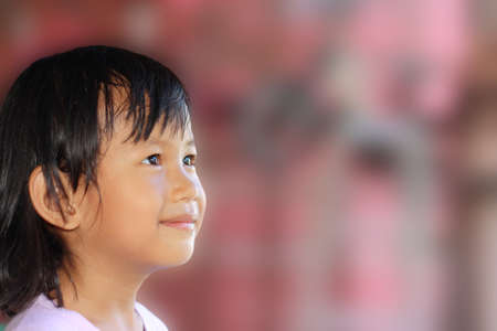Cute Asian child smiling with pink blurred backgroundの写真素材