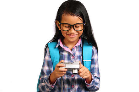 Little girl smiling while checking pictures in her camera isolated on whiteの写真素材