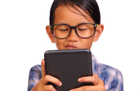 Little girl with glasses seriously playing her tablet isolated on white
