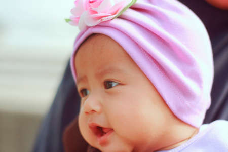 Close up portrait of cute little Asian baby girl wearing head scarf smiling happilyの写真素材