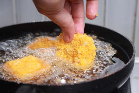 Close up image of chef hand putting chicken nuggets tempura in to hot oil pan for deep fry cookingの写真素材