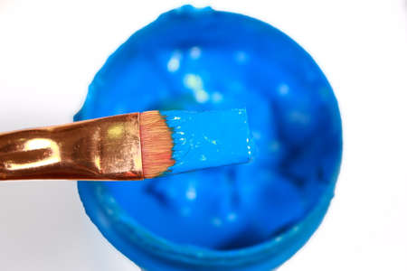 Painting brush with blue acrylic paint in bottle from above view