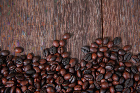Dark roasted coffee beans on dark old wooden table textureの写真素材
