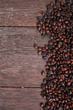 Dark roasted coffee beans on dark old wooden table textureの写真素材